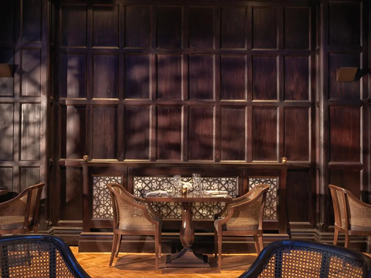 Wooden-panelled dining space with table and chairs at The LaLit London